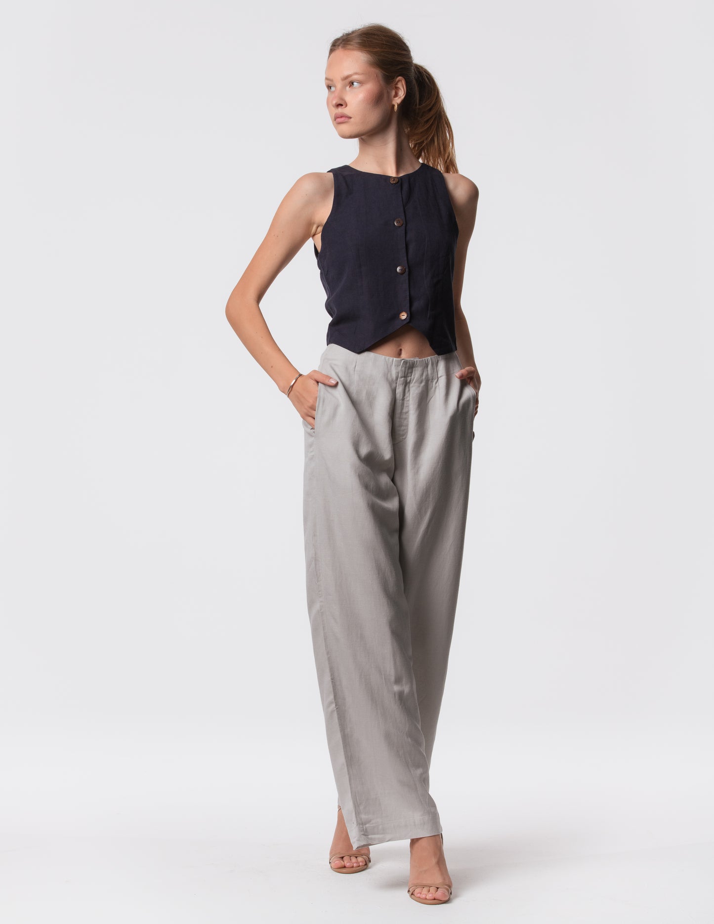Model wearing high-waisted wide-leg linen pants in gray with a relaxed fit and tailored waist by Artemizelle