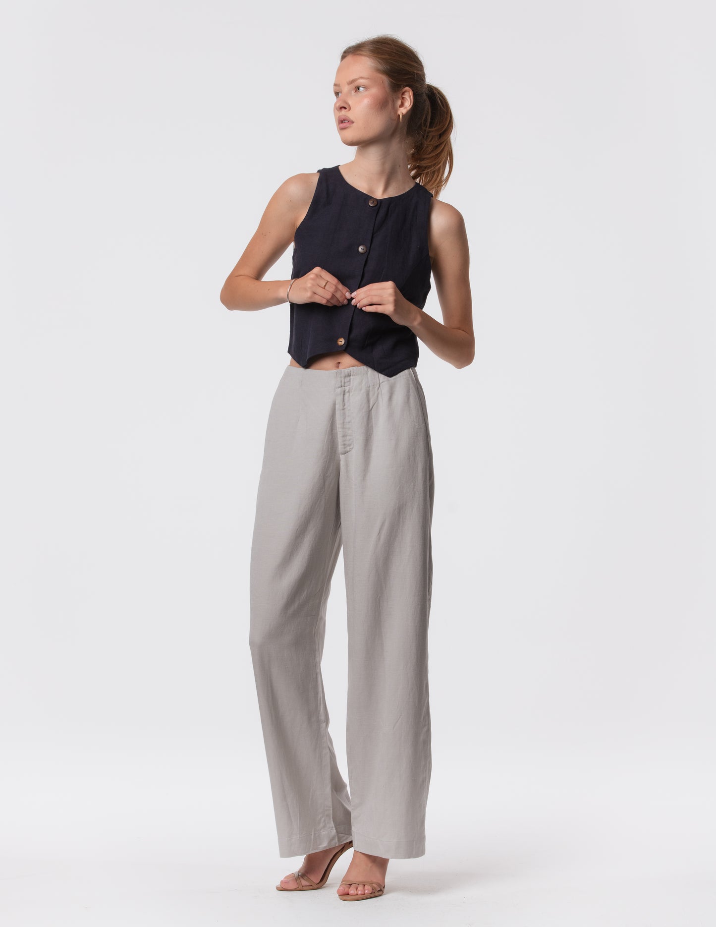 Model wearing high-waisted wide-leg linen pants in gray with a relaxed fit and tailored waist by Artemizelle