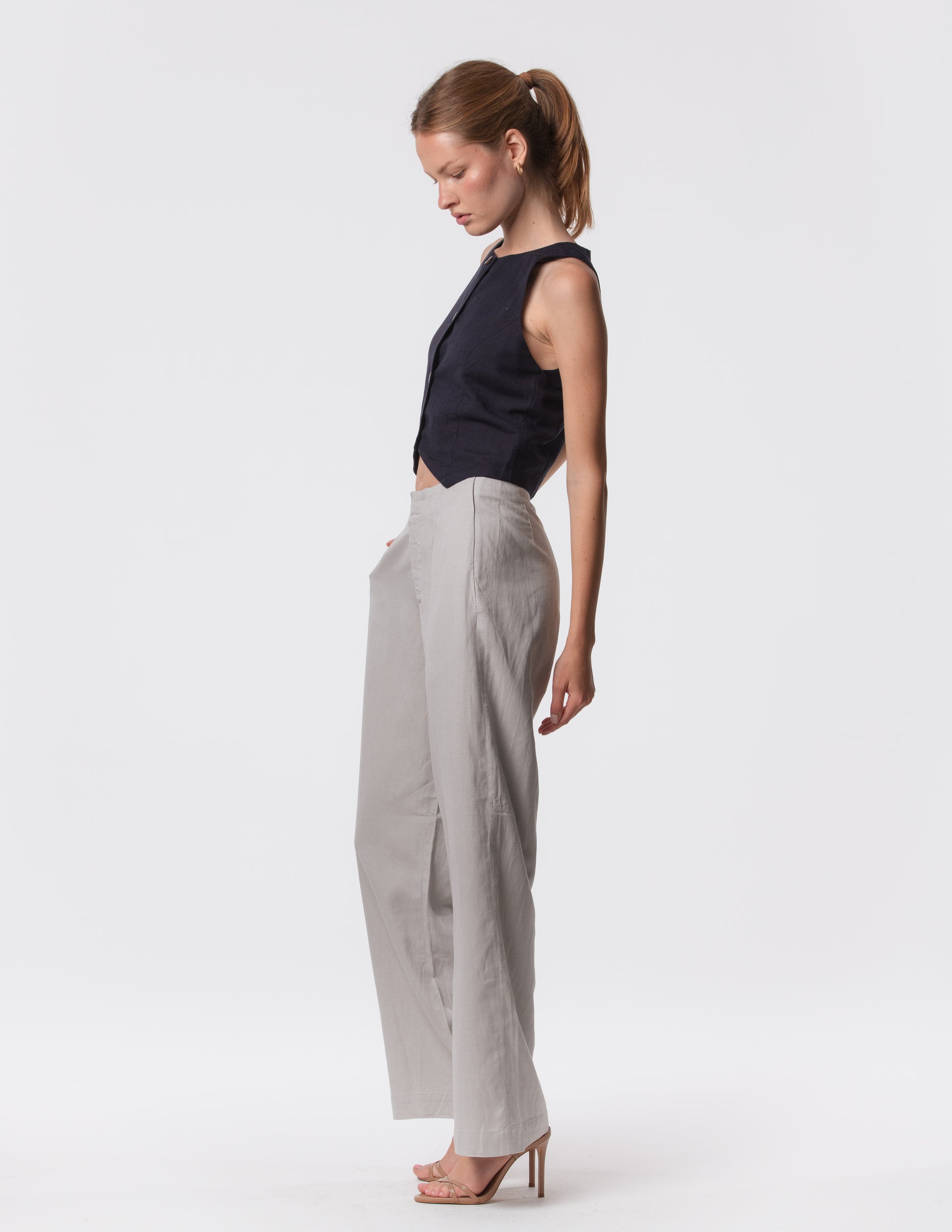 Model wearing high-waisted wide-leg linen pants in gray with a relaxed fit and tailored waist by Artemizelle