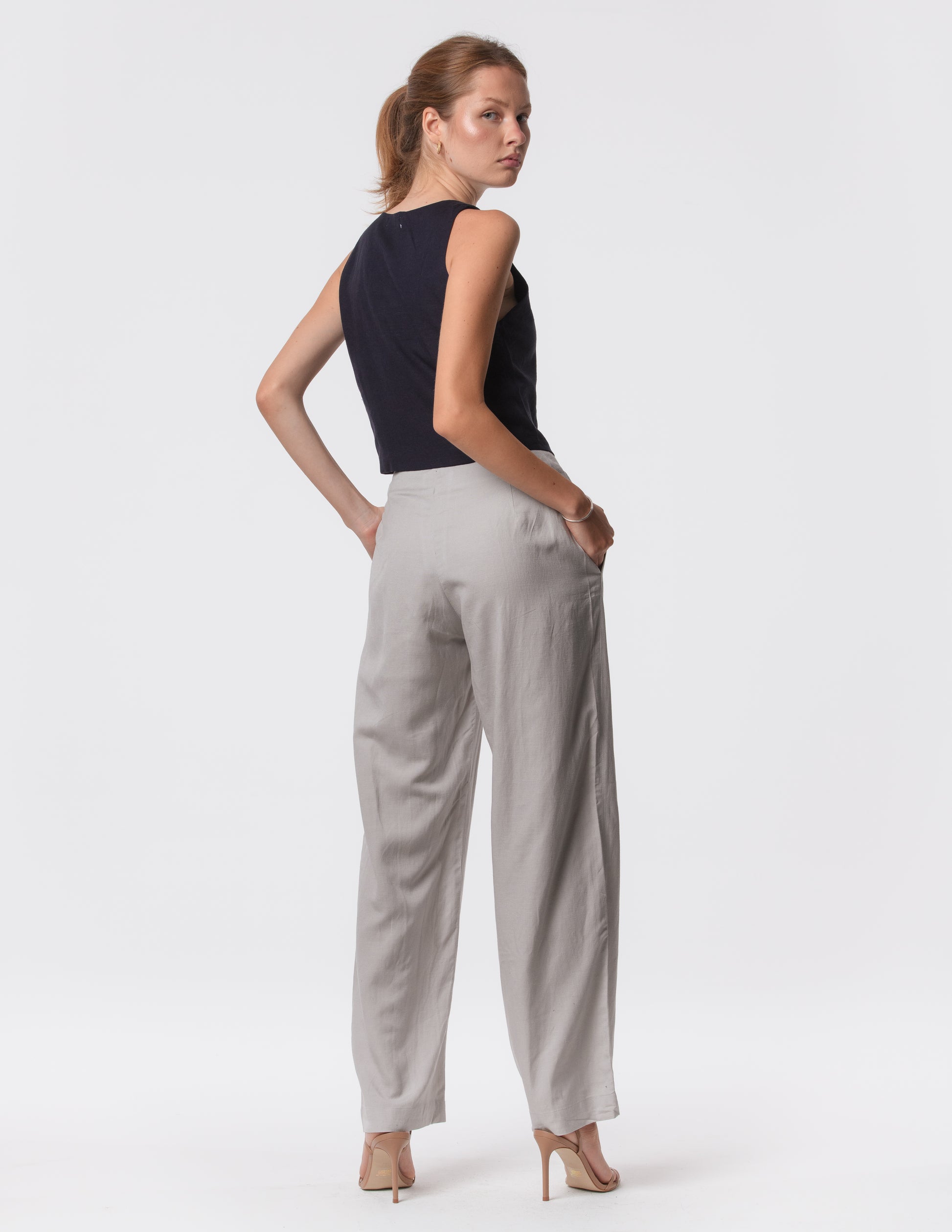 Model wearing high-waisted wide-leg linen pants in gray with a relaxed fit and tailored waist by Artemizelle