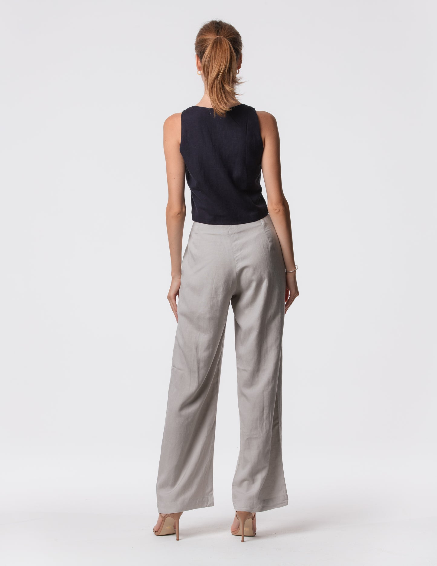 Model wearing high-waisted wide-leg linen pants in gray with a relaxed fit and tailored waist by Artemizelle