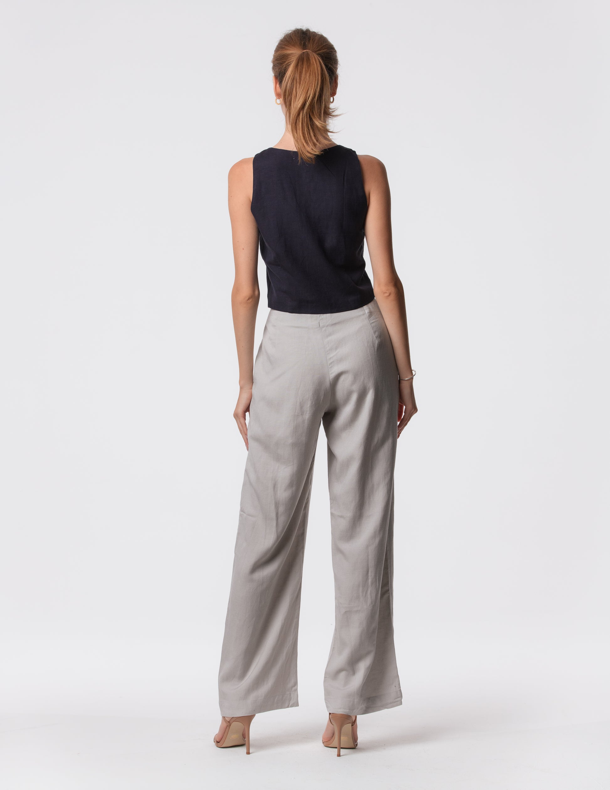 Model wearing high-waisted wide-leg linen pants in gray with a relaxed fit and tailored waist by Artemizelle